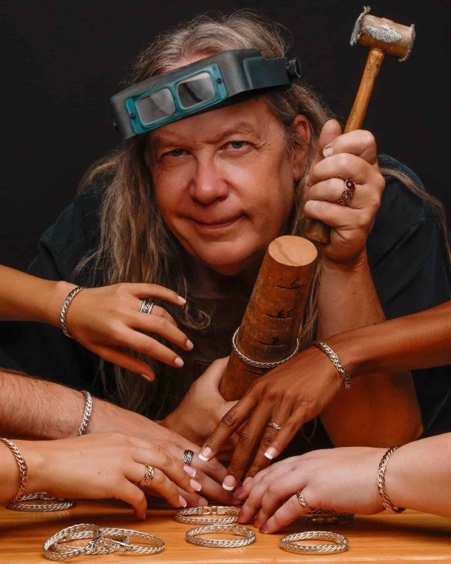 Todd Alan at his jeweler's bench, loupe visor on and hammer in hand