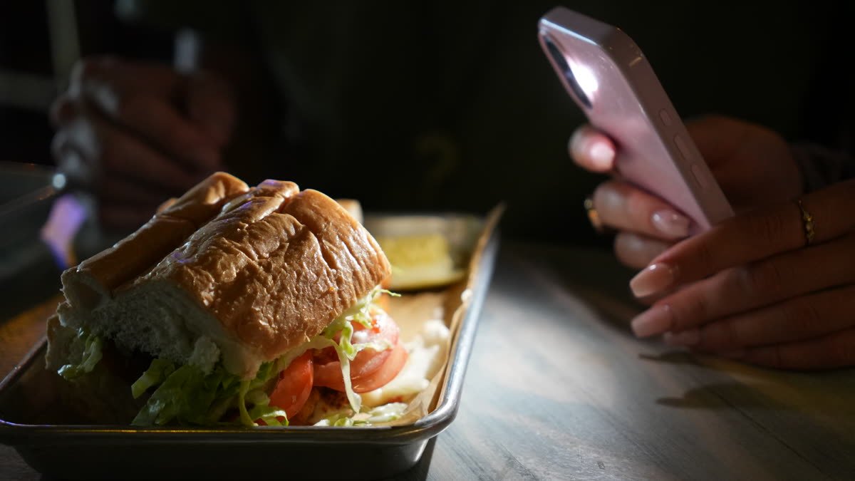 Lucky 8 SRQ kitchen in Sarasota: a sandwich being filmed on a phone by Siesta Media