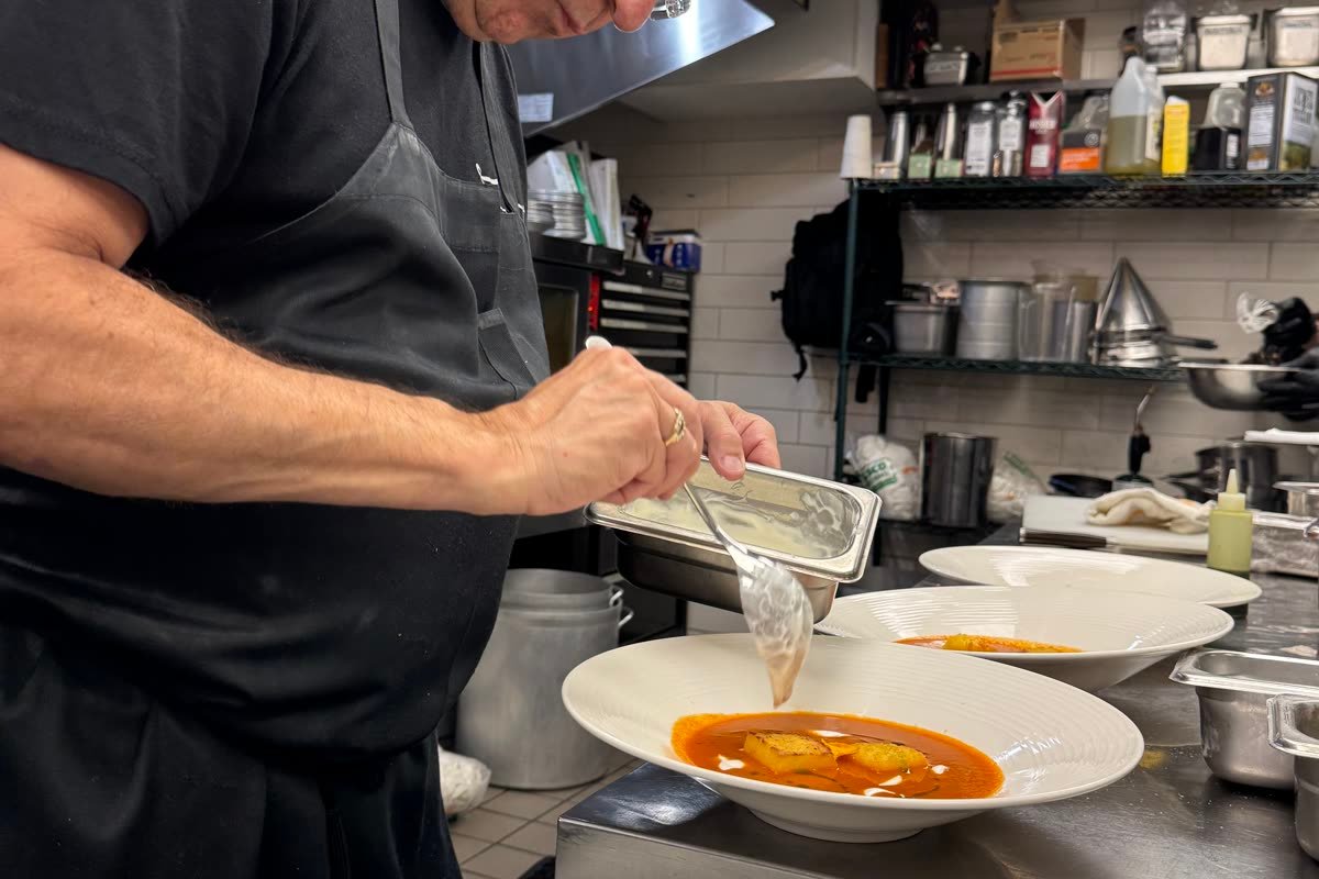 Chef Christopher Covelli plating a dish at the pass at Sage SRQ during a Siesta Media restaurant shoot