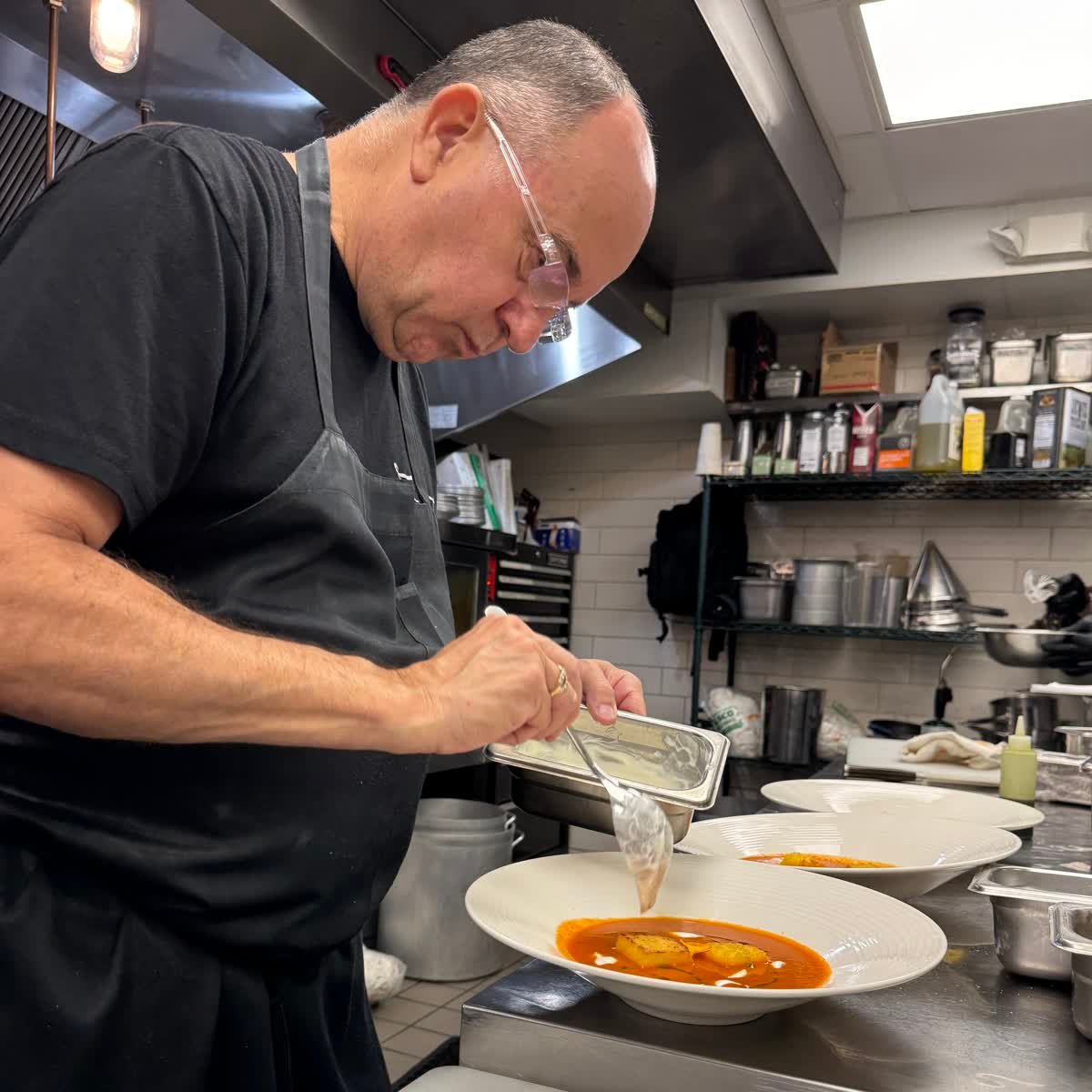 Chef Christopher Covelli plating a dish in the kitchen at Sage SRQ, Sarasota