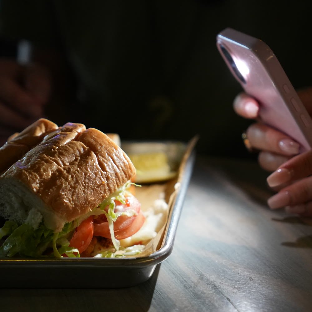 A sandwich on a tray being filmed on a phone during a Siesta Media shoot day in Sarasota