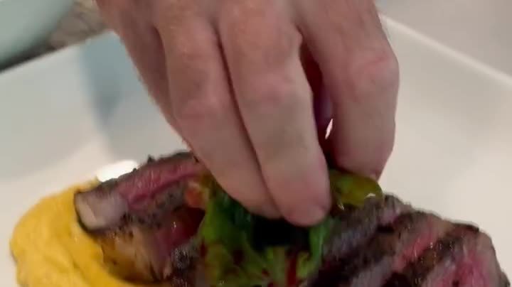 Short-form video frame filmed by Siesta Media for Tamiami Trail Catering: steak plated over polenta